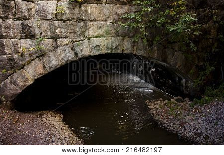 Old Stone Bridge Coverd With Moss And Torrential River.