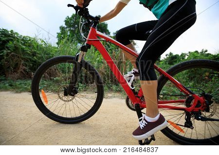 young woman riding mountain bike on forest trail