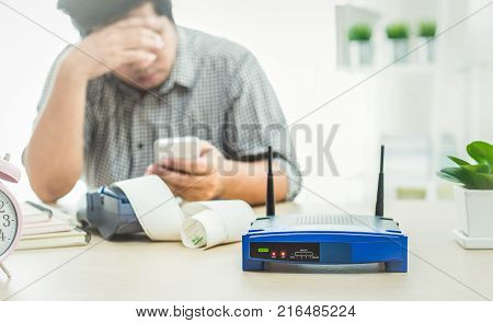 closeup of a wireless router and a man using smart phone on living room at home ofiice network lost