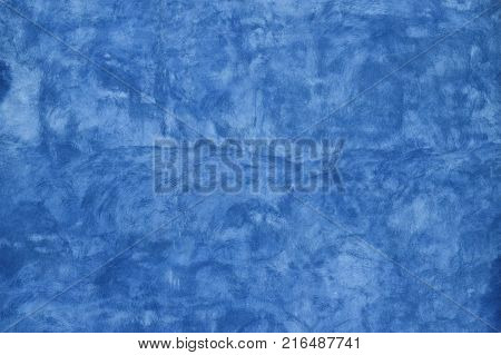Grunge blue faded uneven old aged daub plaster wall texture background with stains and paint strokes, close up