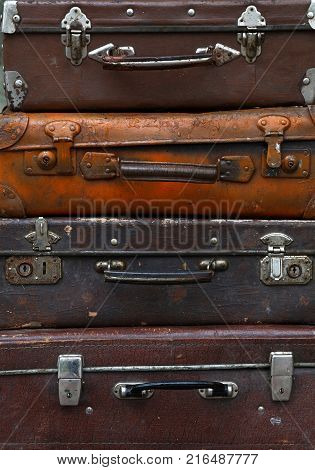 Stack of four old vintage antique grunge travel luggage brown leather suitcase trunks, close up, low angle front view