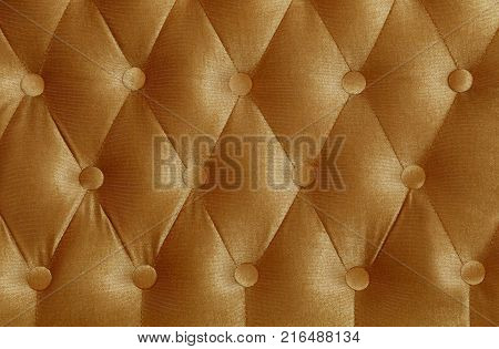Beige brown capitone textile background with buttons, retro Chesterfield style soft tufted fabric furniture upholstery diamond pattern decoration, close up