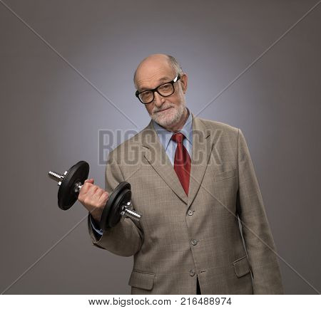 Happy funny senior man in suit with dumbbell power concept