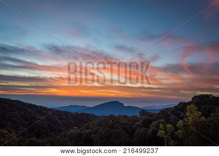 Beautiful sunrise sky and mist green mountain scenery Doi Intanon Thailand with orange clouds.