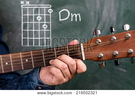 Man playing guitar chords displayed on a blackboard, Chord Dm