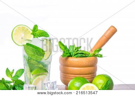 Mojito cocktail with ingredients. Fresh lime mint leaves and ice cubes morter with mint and brown sugar on a wooden background. Refreshing alcohol drink. Isolated on white background.