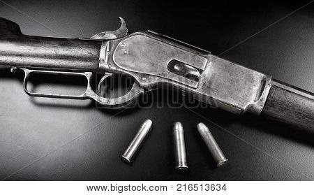 Antique 1876 Cowboy lever action rifle with 45-60 brass bullets in black and white.