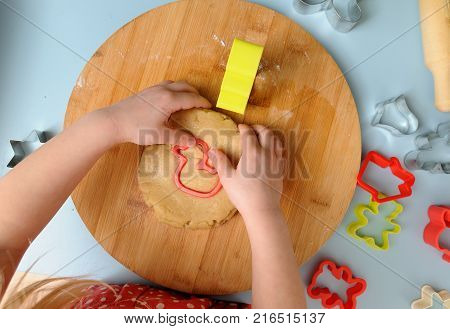 Children in kitchen. Little girl cutting dought with cookie cutter and making duck cookie above view