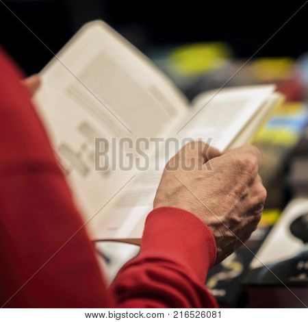Close-up of hands of the elderly person with open book, bookstore, library. Real scene. Education concept, Self-study, reading fiction, pension, interests in the elderly, life style