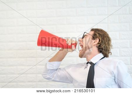 Crazy American Businessman Screaming in Red Megaphone on White Block Background.Side View.
