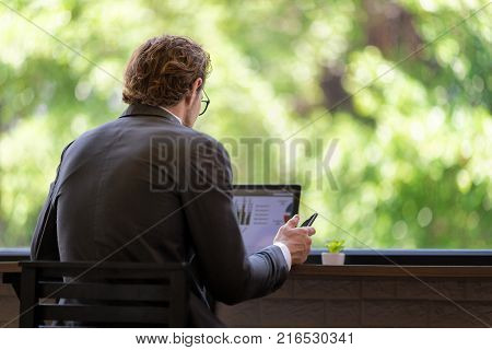 Back Side of Successful Confident of a Businessman using tablet Computer Discussing Analysis in Coffee Shop. Distance Remote Meeting by Internet While Color Chart on Screen. In selective Focus.