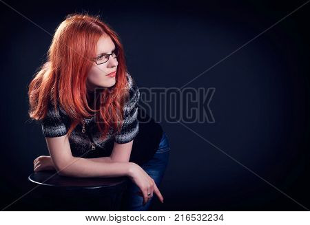 Studio portrait of the beautiful young woman with ginger hair on a dark background