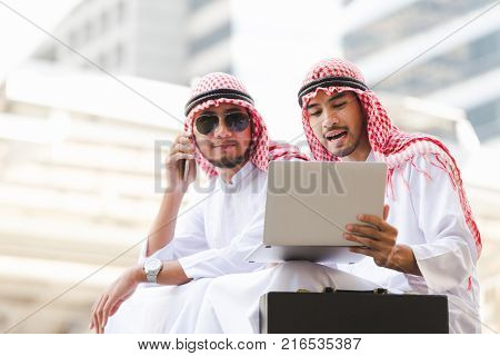 Arab business man call phone working on taplet in the city