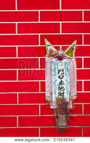 HONG KONG - OCT 14, 2013 - Small shrine to the earth god Tu Di mounted on a red tiled wall in Hong Kong. The text reads mén​k