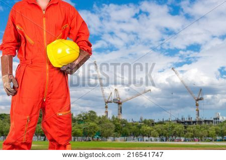 Asian engineers holding a yellow hardhat on Under construction four cranes with cloud on blue sky constructure industrial concept