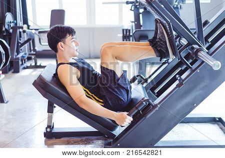 Handsome muscular man working out with leg press to define his upper leg muscles at the gymFitness and Healthy Lifstyle Concept.