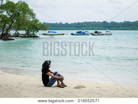 Girl Sitting on a Beach alone looking at the blue sea