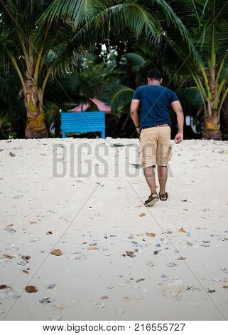 Man Walking Towards a Bench on a Beach