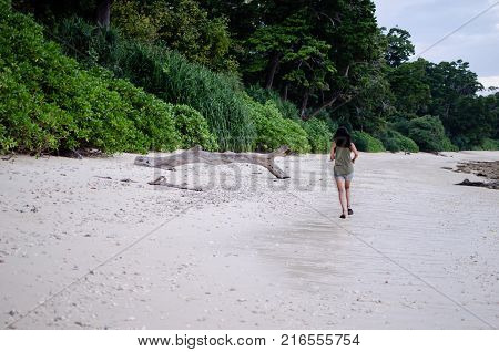 Girl Running on a Beach towards a fallen piece of wood bark