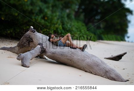 Women Traveler relaxing on a Fallen Tree on a Beach