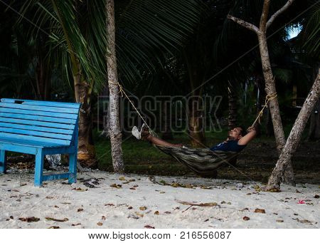 Man Sleeping on a Hammock or a net near on a Beach
