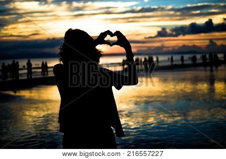 Girl Doing Heart Shape with Hands in Sunset