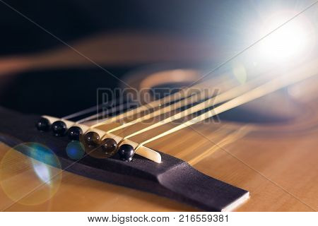 Close-up of rosette and strings of the acoustic guitar on black background.