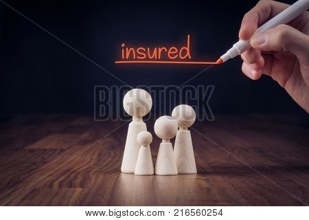 Family life insurance concept. Wooden figurines representing family and hand writing text insured.