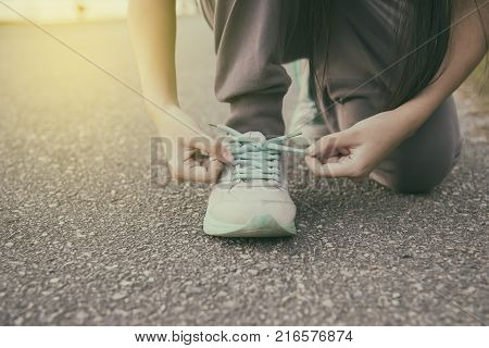 Female runner tying her shoes preparing for jogging outside .Young girld runner getting ready for training. Sport lifestyle