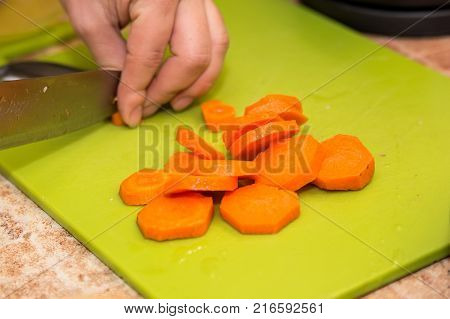Closeup image of hands with knife cutting carrot