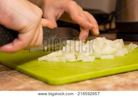 Closeup image of hands with knife cutting onion