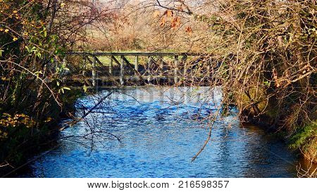Wooden bridge on the blue river in the nature