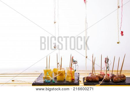 Party food leftovers. Cheese and pineapple and cocktail sausages on sticks. Leftover nibbles with party popper streamers in front of white background with copy space.