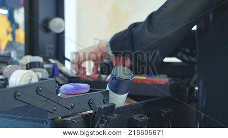 Professional makeup artist selecting tools and cosmetics in make-up suitcase at beauty salon close-up