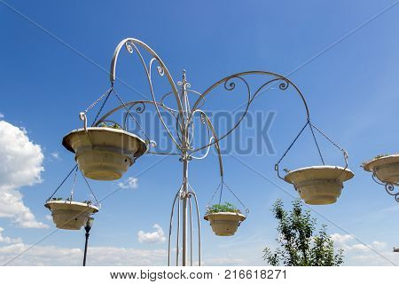 TAGANROG RUSSIA - June 20 2017: Pots of a bed of flowers are suspended on a stand against the background of the blue sky the central embankment of Taganrog in the summer afternoon