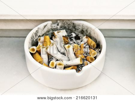 Cigarette butts in a ceramic ashtray smoking in public places.