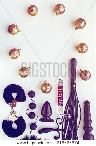 Various sex toys and Christmas decorations on a light background. Image for the festive season, for sales and discounts in sex shops. There is a blank space for text. Vertical image