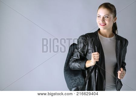 Portrait of beautiful young brunette woman in stylish black jacket on gray