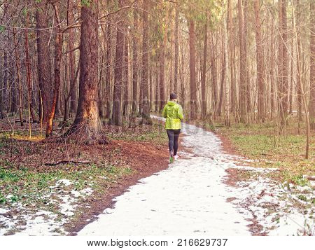 The girl runs along the snow trail in the autumn forest. Image on the topic of maintaining the body in good physical shape, strengthening health and immunity, a healthy lifestyle