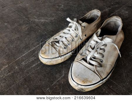dirty and old white shoes on dirty cement ground