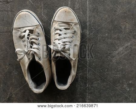 dirty and old white shoes on dirty cement ground
