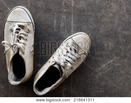 dirty and old white shoes on dirty cement ground