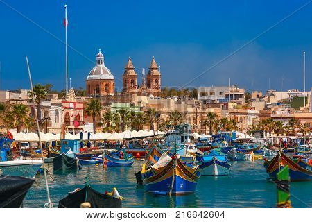 Traditional eyed colorful boats Luzzu in the Harbor of Mediterranean fishing village Marsaxlokk, Malta