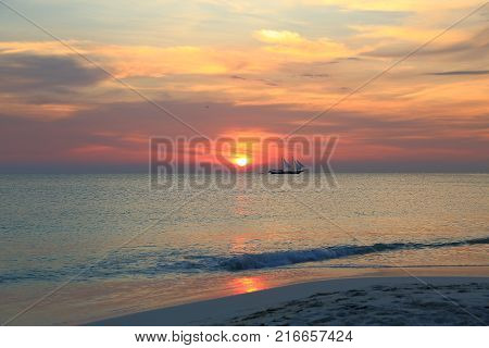 Gorgeous colorful sunset on Caribbean sea, Unforgettable view of Aruba landscape. Small boat on horizon line.