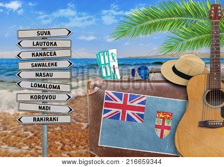 Concept of summer traveling with old suitcase and Fiji town sign
