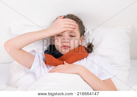child in bed holds a hand on his forehead reducing pain