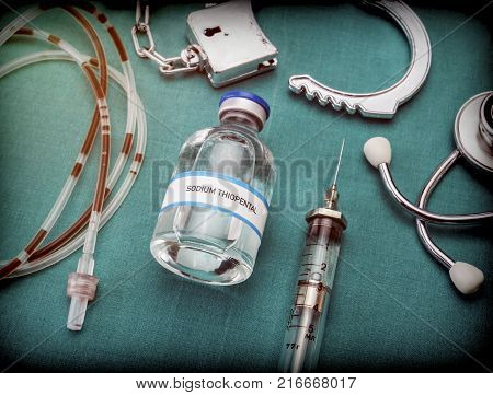 Handcuffs next to a vial of sodium thiopental and drip irrigation equipment with traces of blood, concept of capital punishment, conceptual image