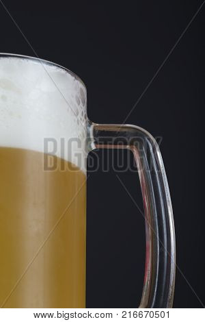 A glass of beer on a dark background with space for text. A mug of beer with foam. A glass of cold beer close up. A glass of unfiltered beer with condensation. The swirling mug of light beer.