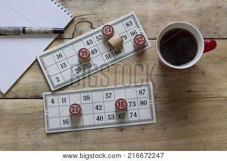 Cards And Chips For Playing Bingo On A Wooden Table. Cup With Coffee