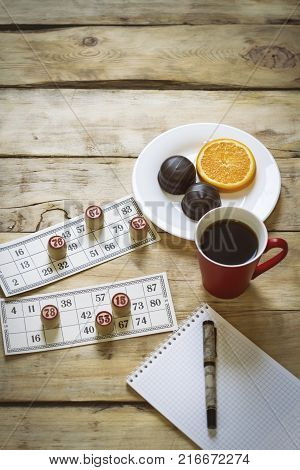 Cards And Chips For Playing Bingo On A Wooden Table. Cup With Coffee